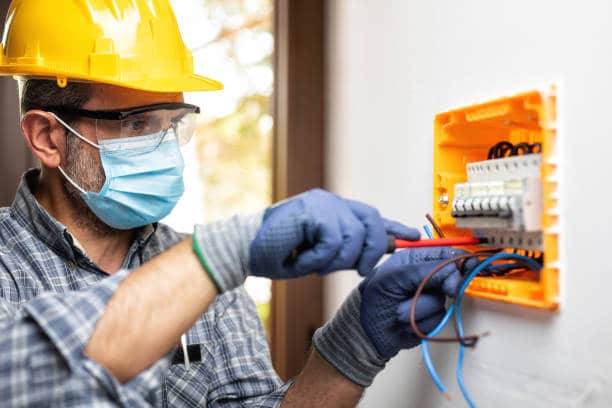 Electrician at work on an electrical panel protected by helmet and gloves