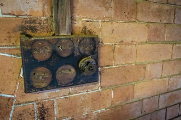 A set of broken light switches attached to a wall outside of the house