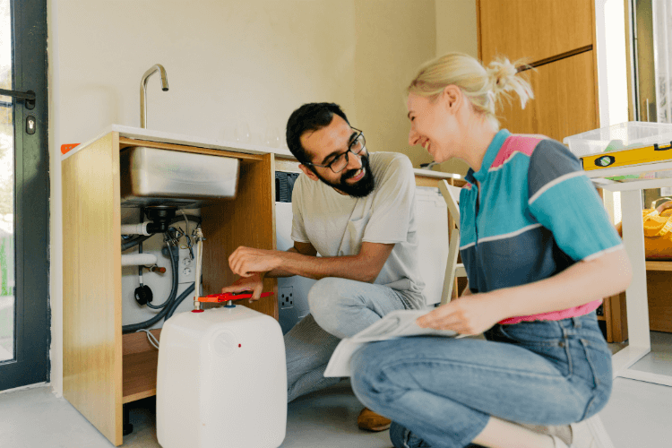 Couple doing some DIY plumbing repairs at home.