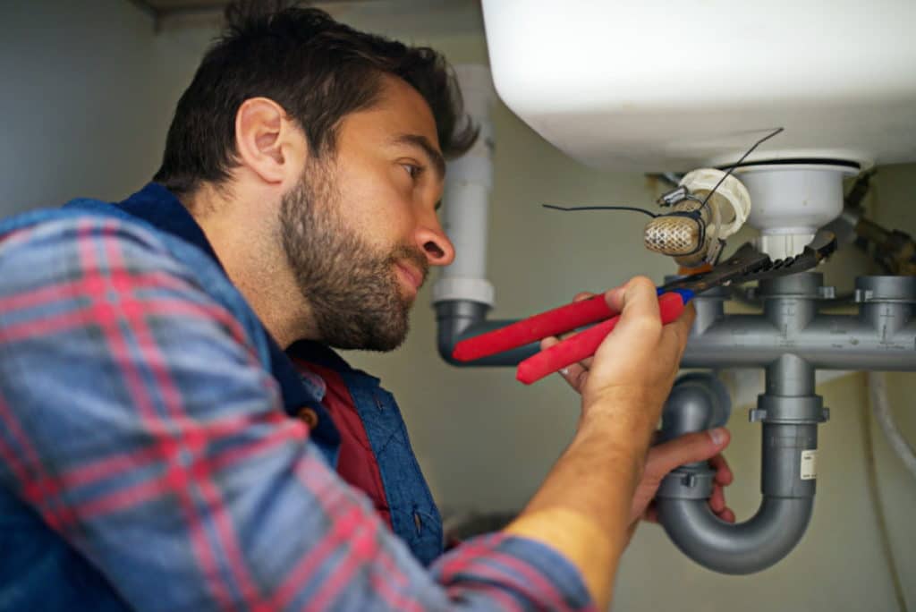 Professional plumber fixing a bathroom sink.