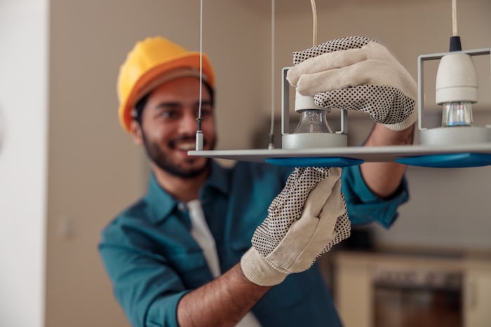 electrician smiling while installing lighting in commercial space
